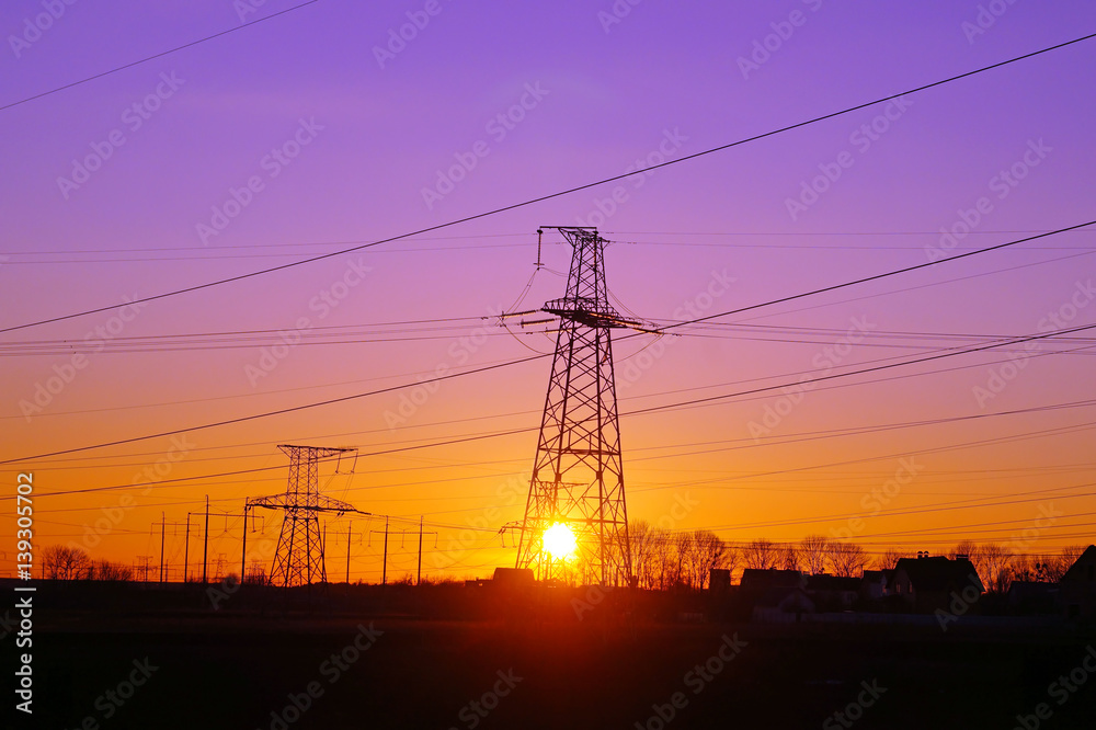 High voltage distribution power lines pylon at sunset