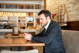 Businessman is sitting in restaurant and using his phone
