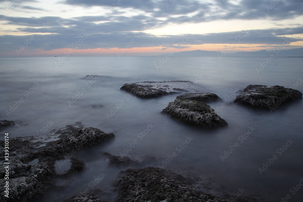 Sea coast in a long exposure shot at sunset, with blurred water