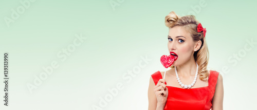 young woman eating colourful lollipop, dressed in pin-up style © vgstudio