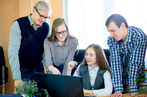 four employees looking at laptop