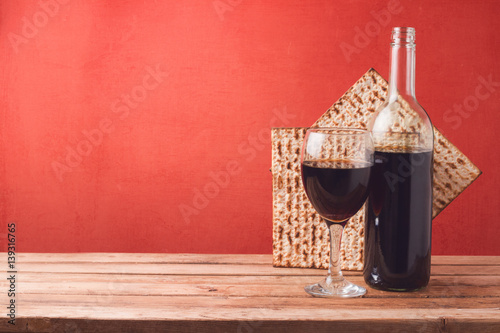 Passover holiday concept with wine and matzoh on wooden table over red background