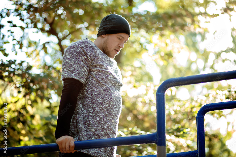 Naklejka premium Healthy handsome active man with fit muscular body doing workout exercises. Outdoor, park. Sports and fitness concept