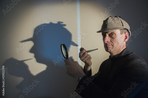 sherlock holmes in studio detective at work with magnifying glass and pipe photo