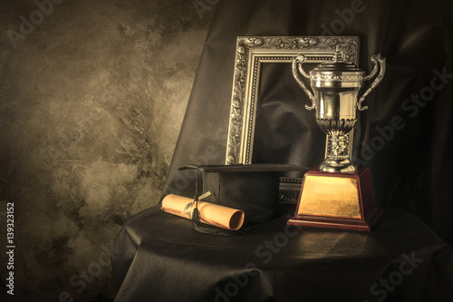 picture frame, trophy cup and graduates still life photography success concept background.
