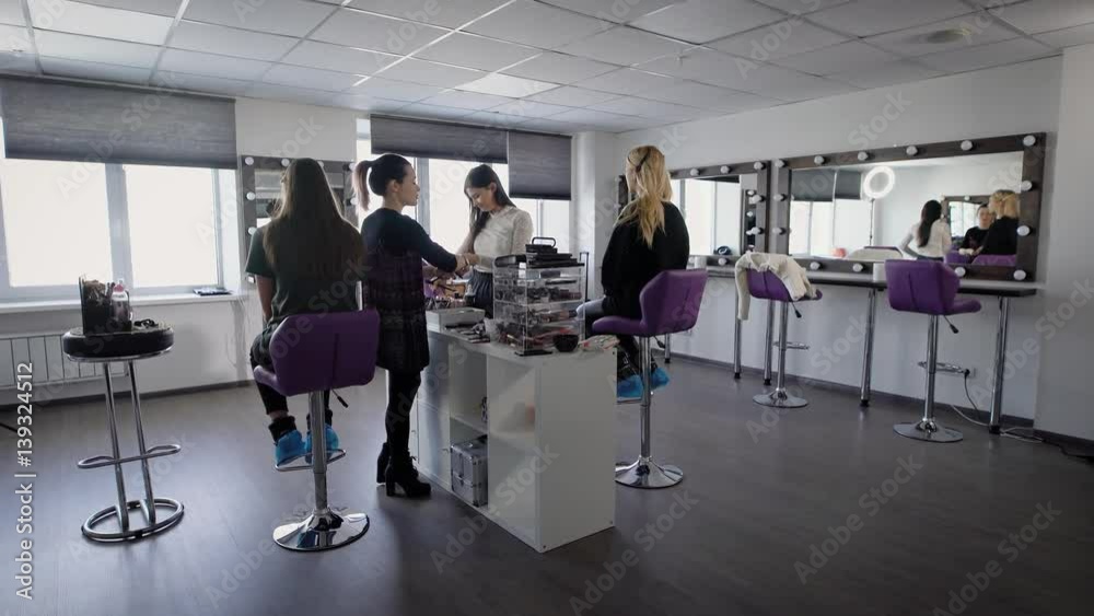 Interior of luxury beauty salon with two professional experts and two female models sitting. Professional visagistes are working with young girls applying new techniques of make-up. Interior of luxury beauty salon with two professional experts and two female models sitting. Professional visagistes are working with young girls applying new techniques of make-up.