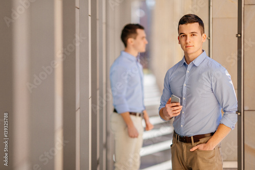 Businessman talking at his phone with friend on blur background
