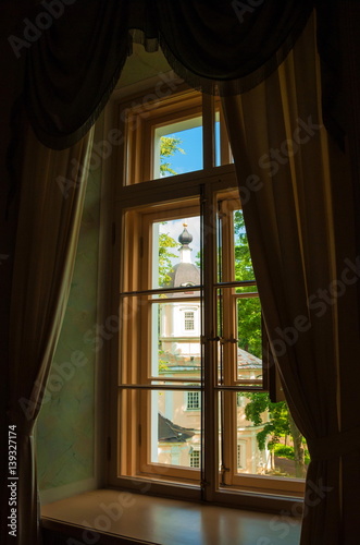 Window with beautiful curtains overlooking the ancient church in the park