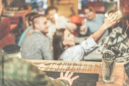 Barman view of happy friends taking selfie with mobile smart phone in cocktail pub bar