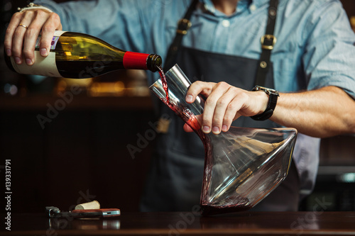 Sommelier pouring red wine into carafe to make perfect color