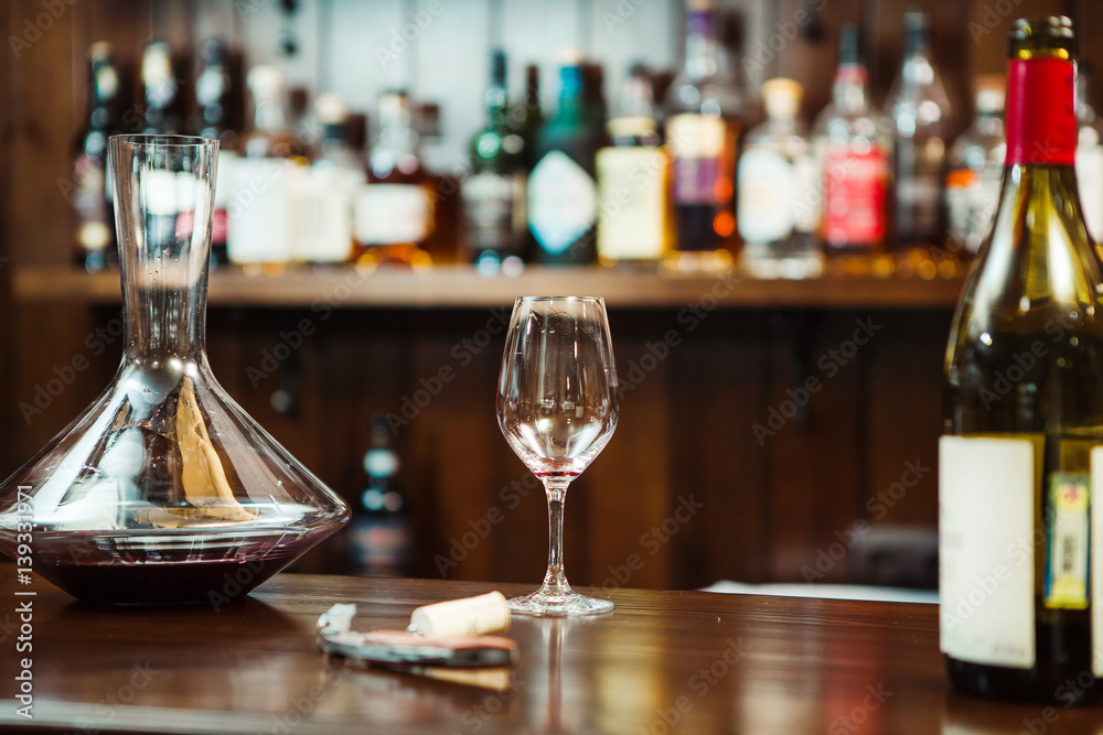 Decanter with wine and a glass on the bar counter
