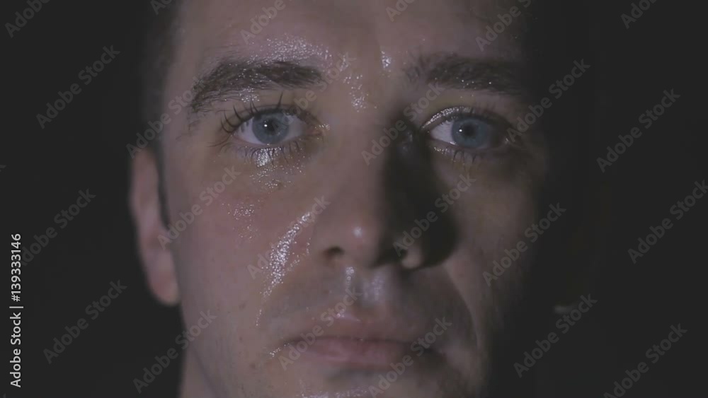 Intense sweaty face of young muscular man pulling rope