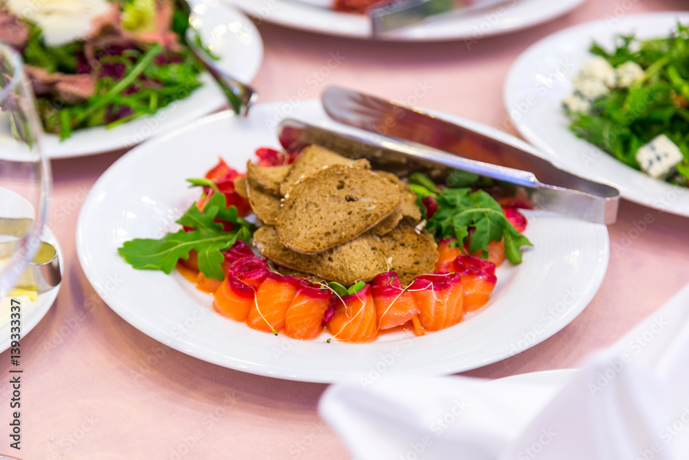 Red fish sliced on a plate. Sliced red fish salmon greens lemon black olives on plate Red fish sliced on a plate. Sliced red fish salmon greens lemon black olives on plate