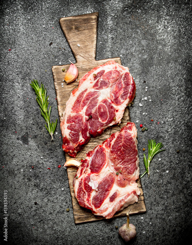 Raw meat background. A piece of Raw pork chops with fragrant spices and fresh herbs. On rustic background.