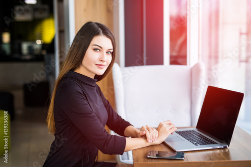 Side view of a young businesswoman using laptop in cafe