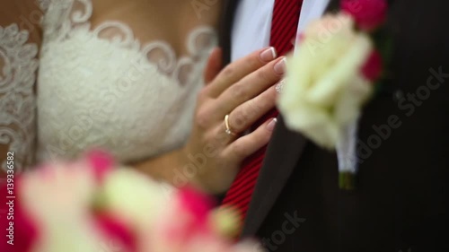bride hugs groom holding hand with bouquet of peonies before groom's chest