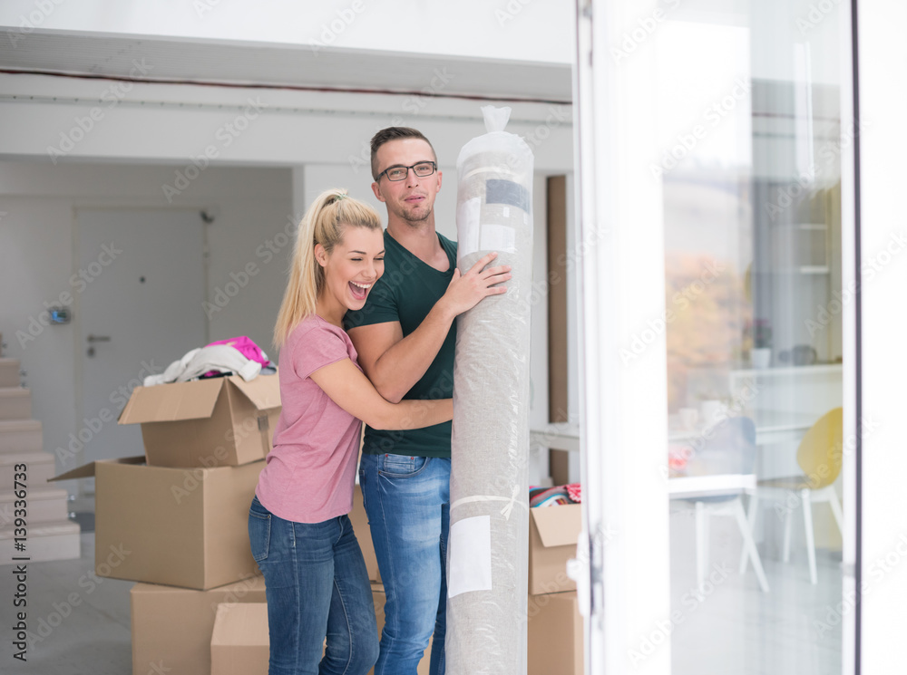 couple carrying a carpet moving in to new home