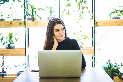 Portrait of attractive business woman sitting in chait and working at laptop online. photo