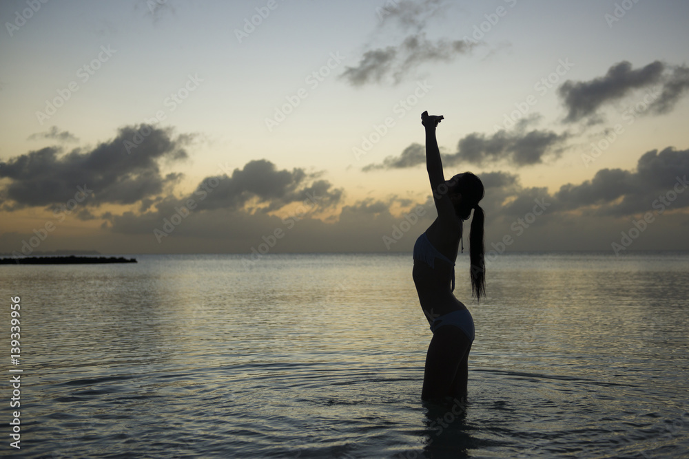 Fototapeta premium 夕暮れの海で寛ぐ美しい女性