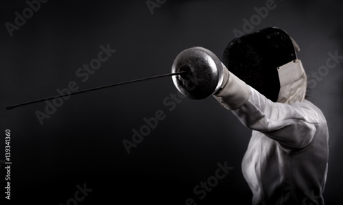 Fotografie Portrait of woman wearing white fencing costume practicing with the sword