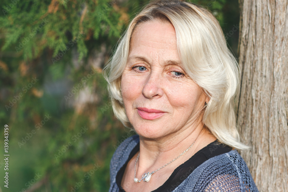 Portrait of senior woman leaning on a tree in the park. Portrait of senior woman leaning on a tree in the park.