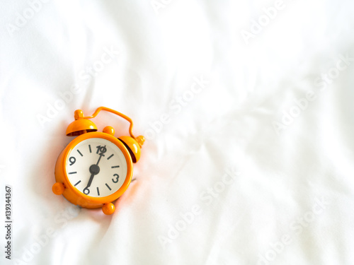 Alarm clock on bed in morning with sun light