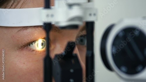 Dolly sliding towards female patient with head in medical device for examining eye structure.