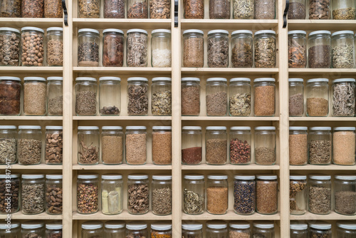Glass bottles with colorful spices on the shelfs