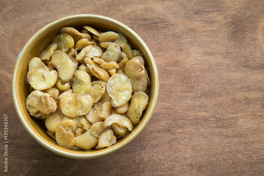 Salted broad beans in bowl on wooden background. Salted broad beans in bowl on wooden background.
