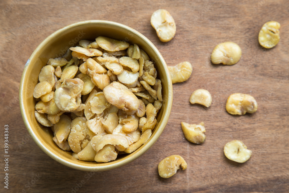 Salted broad beans in bowl on wooden background. Salted broad beans in bowl on wooden background.