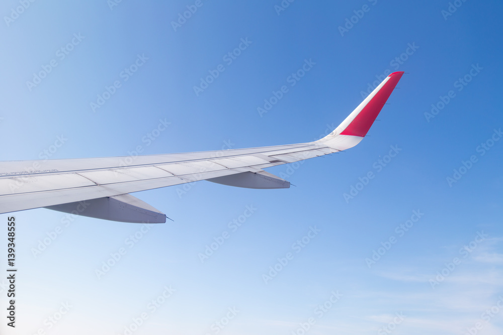 Fototapeta premium Wing of an airplane flying above the blue sky and clouds.