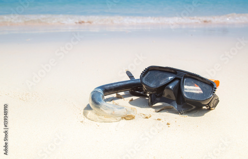 Mask and snorkel in the surf on the sandy beach.