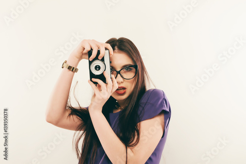 Young smiling woman making a photo through old photo camera. Photographer
