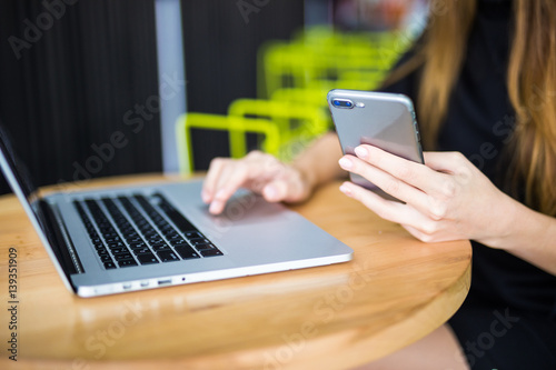 Female hands typing on computer keyboard and phone