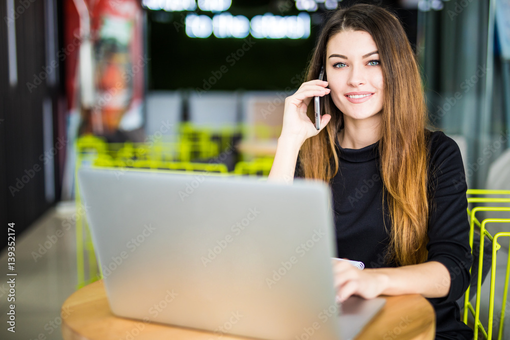 Happy pretty manager talking on mobile phone with client in modern office