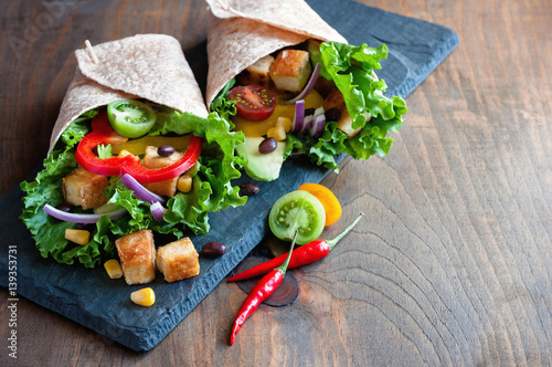 Tortilla wrap or burrito with tofu, greens, and vegetables, vegetarian healthy food, toned image