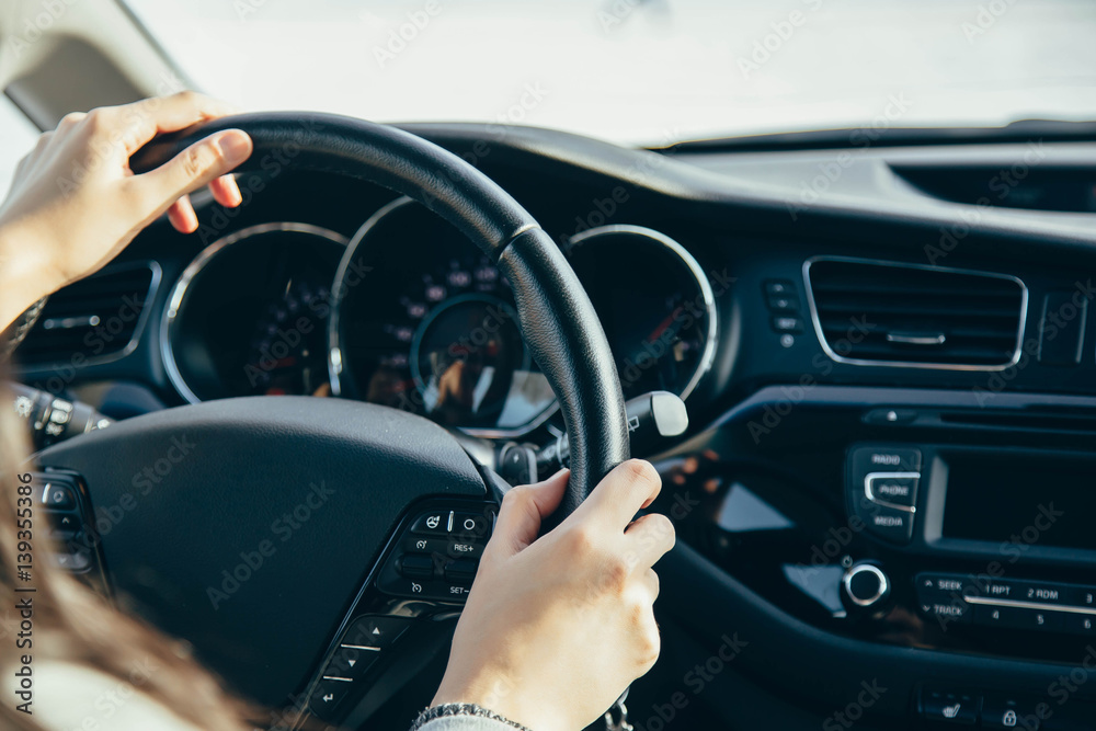 Female hand on the driving wheels. Driving a modern car steering wheel and hand close-up.