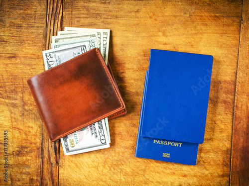 Money in wallet and passports for travel on wooden table