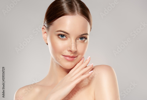 Beautiful Young Woman with Clean Fresh Skin touch own face . Facial treatment . Cosmetology , beauty and spa 