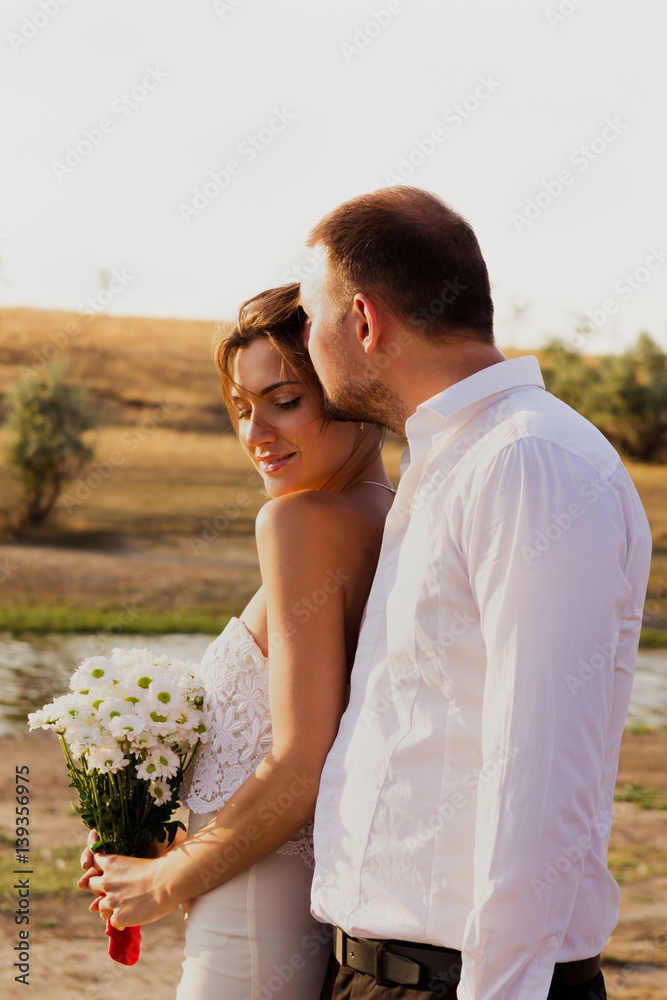 A beautiful romantic couple man and woman in white dresses outdoors A beautiful romantic couple man and woman in white dresses outdoors