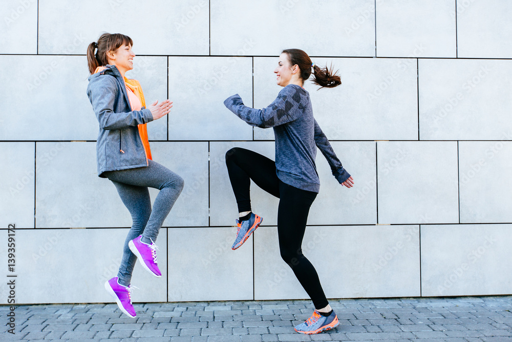 Fototapeta premium Full leight of two sporty women face to face exercising for marathon and workout fitness