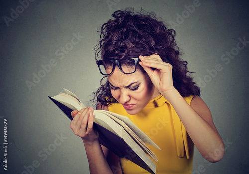 Fototapeta Naklejka Na Ścianę i Meble -  Woman with glasses reading book has eyesight problems