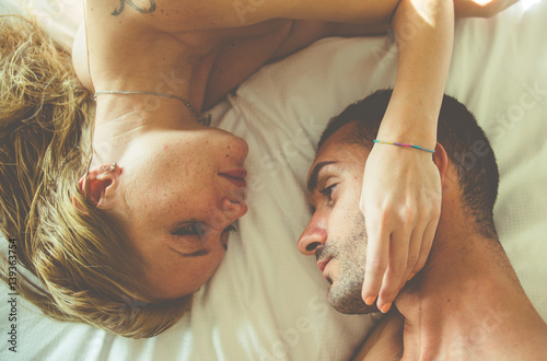 Young couple kissing in bed with inverted position photo