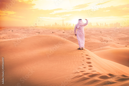 Foto Arabic man with traditional emirates clothes walking in the desert