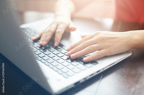 People and modern technology concept. Close up shot of female hands typing on keyboard of her laptop. Young businesswoman working on notebook computer at office. Female freelancer typing messages