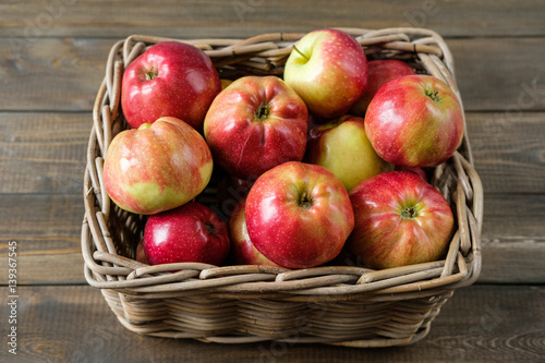 basket with red ripe apples on a brown wooden table