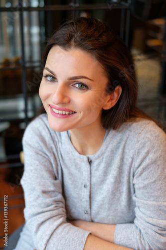Portrait of young beautiful happy woman. Girl sits at a table in a cafe.