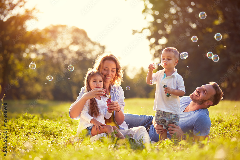 Family with children blow soap bubbles outdoor - obrazy, fototapety, plakaty 