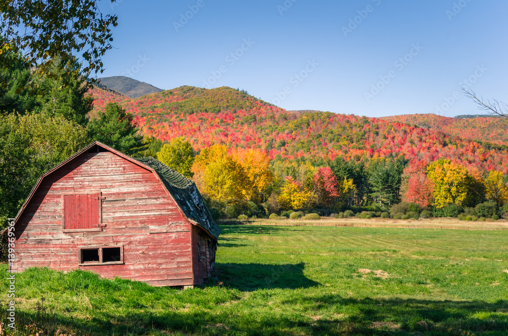 Disused Old Red Barn with Forested Mountains in Background on a Clear Autumn Day. Beautiful Autumn Colours. Disused Old Red Barn with Forested Mountains in Background on a Clear Autumn Day. Beautiful Autumn Colours.