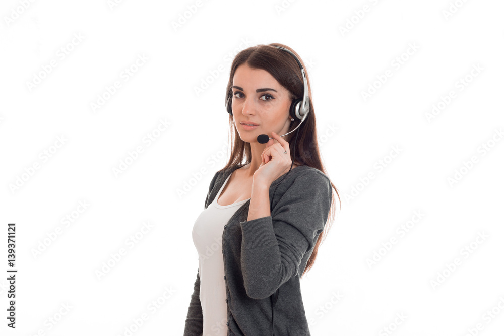 beautiful young girl in headphones and gray jacket looks into the camera and holds hand microphone beautiful young girl in headphones and gray jacket looks into the camera and holds hand microphone